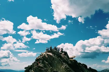 Hikers on a rocky summit under a cloud-filled sky